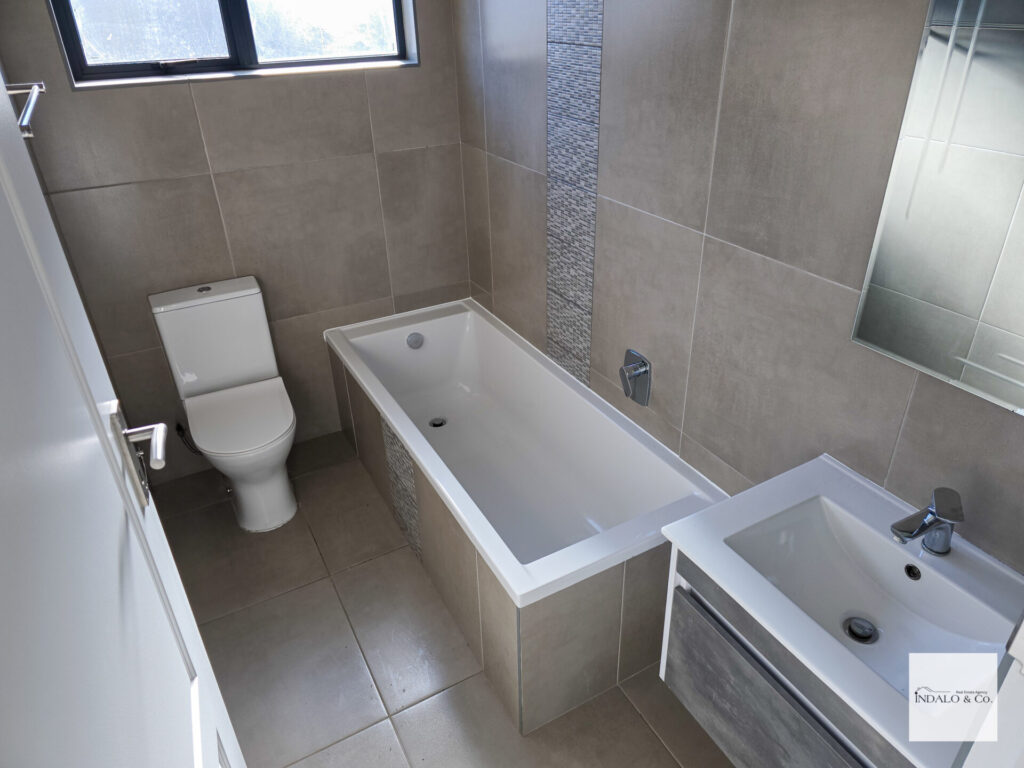 Tiled bathroom with a bathtub, toilet and basin
