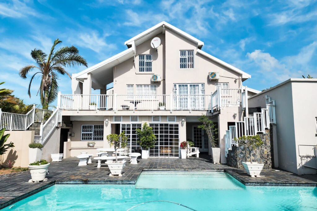 White multi-storey home with a swimming pool and outdoor seating