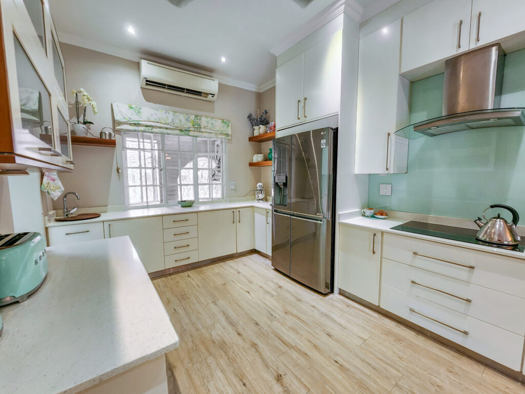 White kitchen with a stainless-steel fridge and pale green splashback