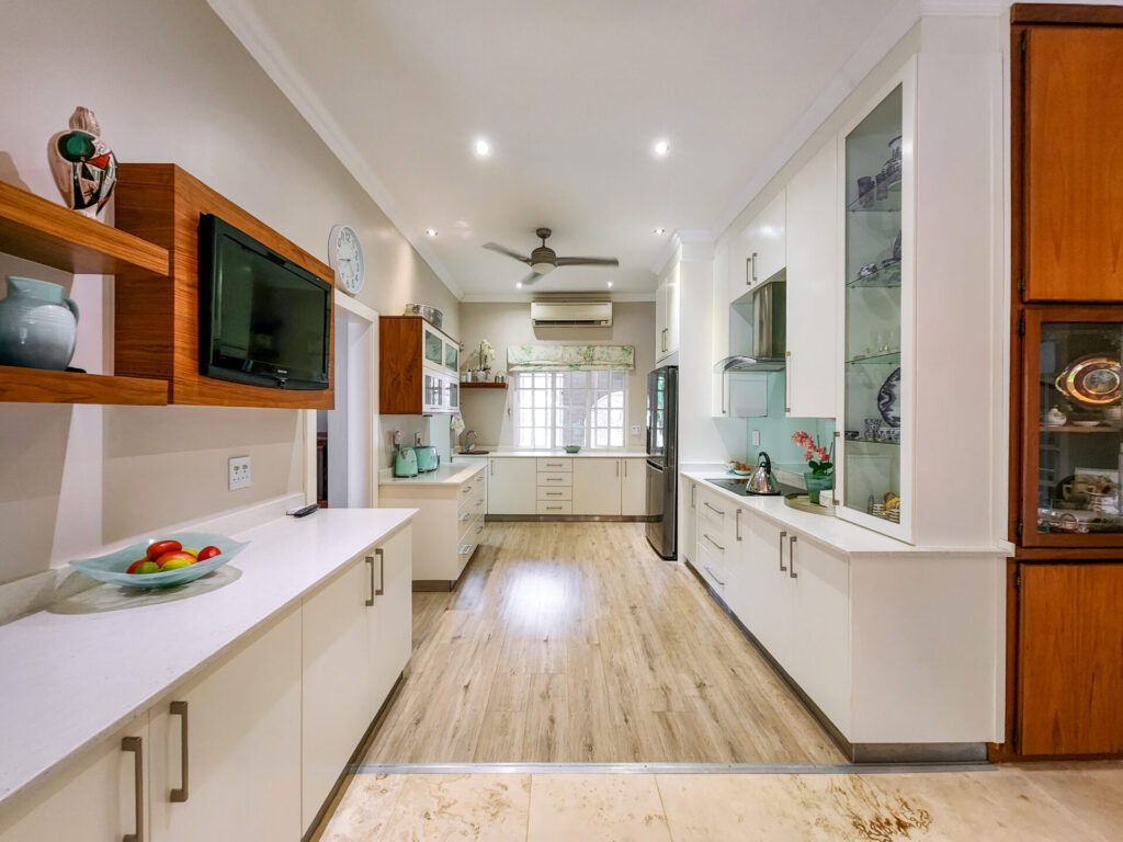 Galley kitchen with white cabinetry, timber accents and wood-look flooring