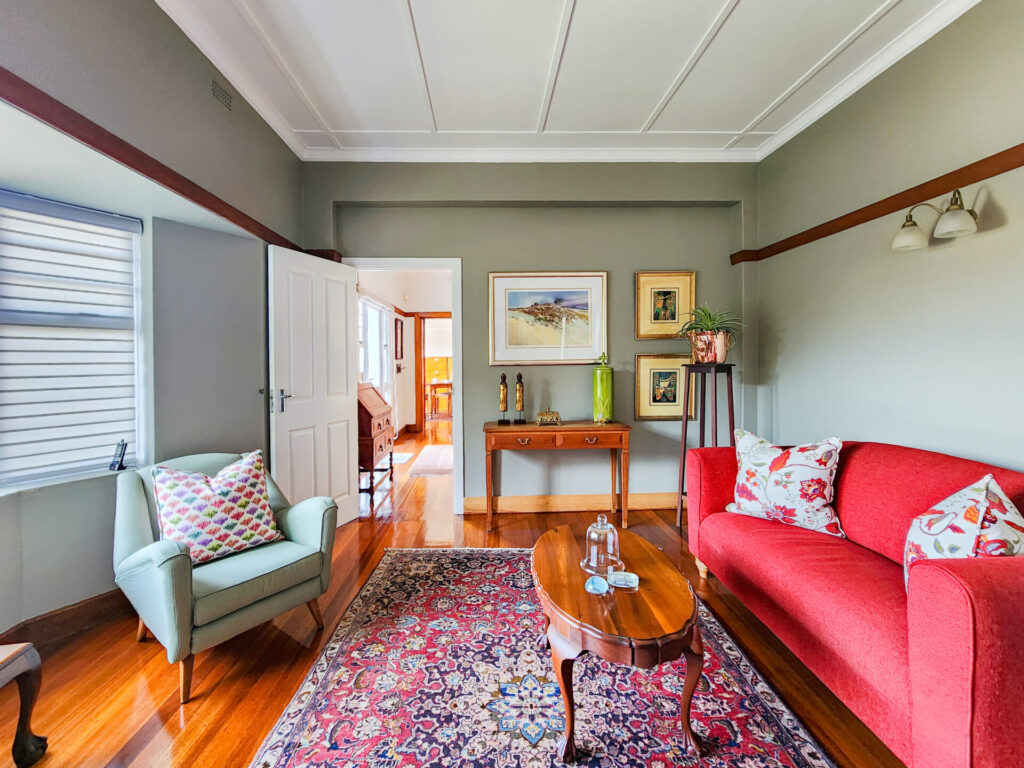 Living room with a red sofa, framed artwork and timber flooring