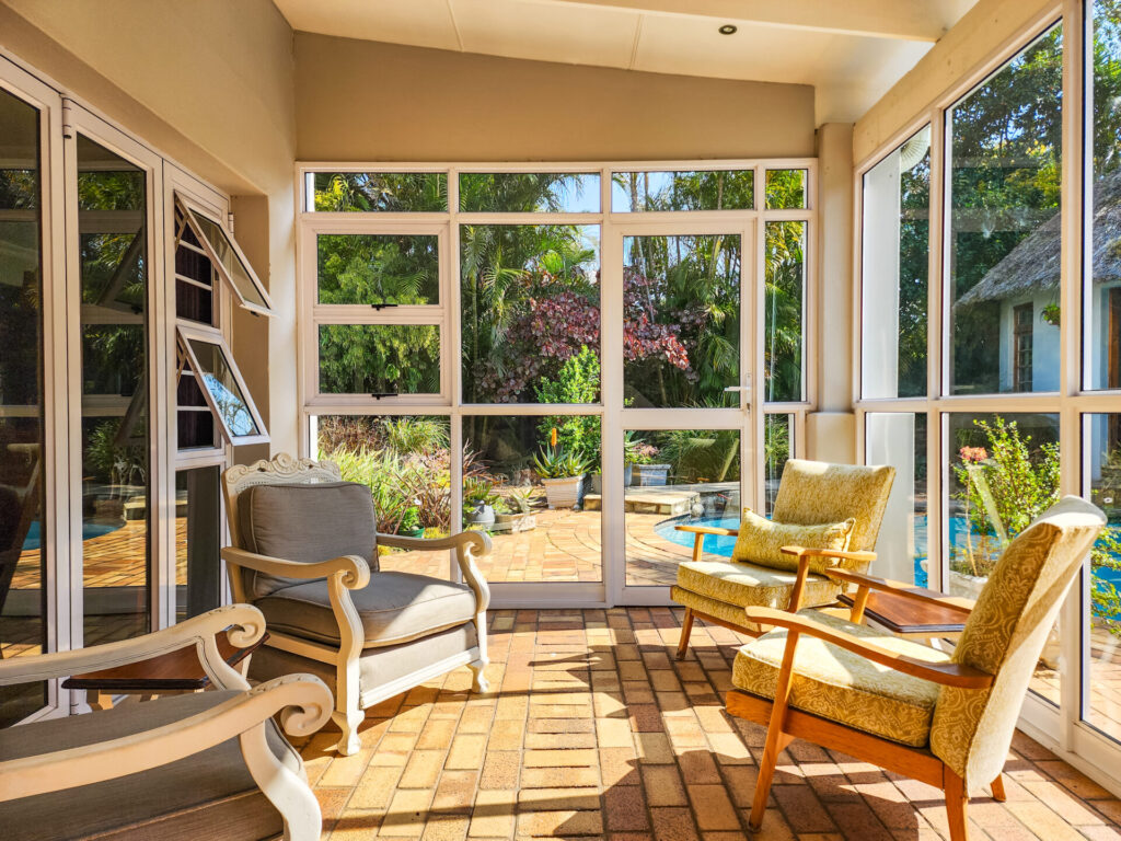 Sunroom with timber flooring, wicker chairs and garden views
