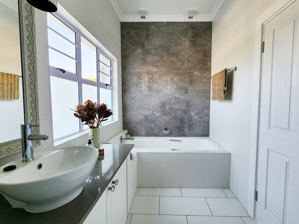 Bathroom with a freestanding basin, bathtub and grey feature wall
