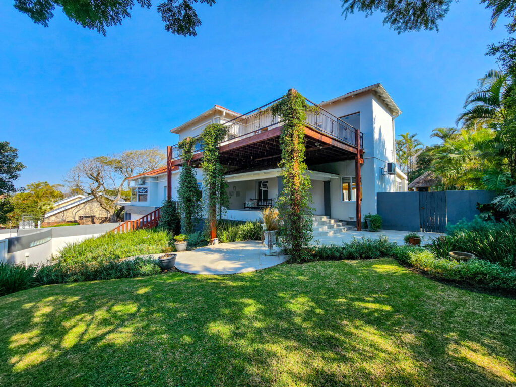 Garden view of a multi-storey home with a covered balcony