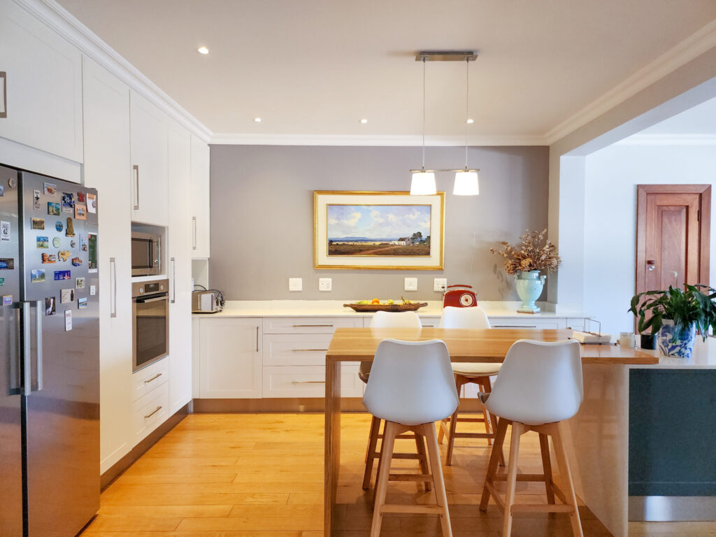 White kitchen and dining area with a timber table and pale chairs