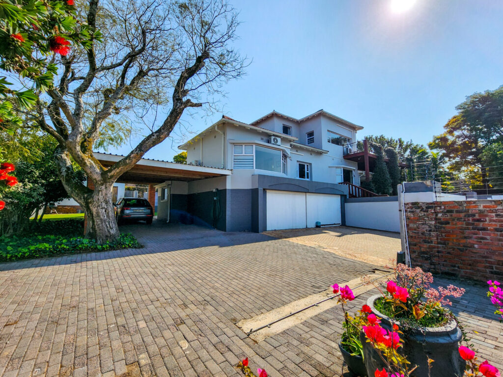 Paved driveway leading to a multi-storey home with garages