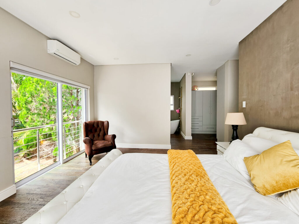 Bedroom with white bedding and glazed doors opening onto greenery