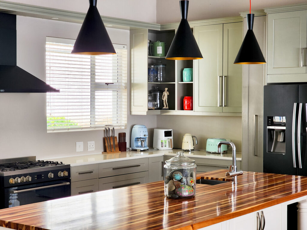 Kitchen with black pendant lights above a timber-topped island