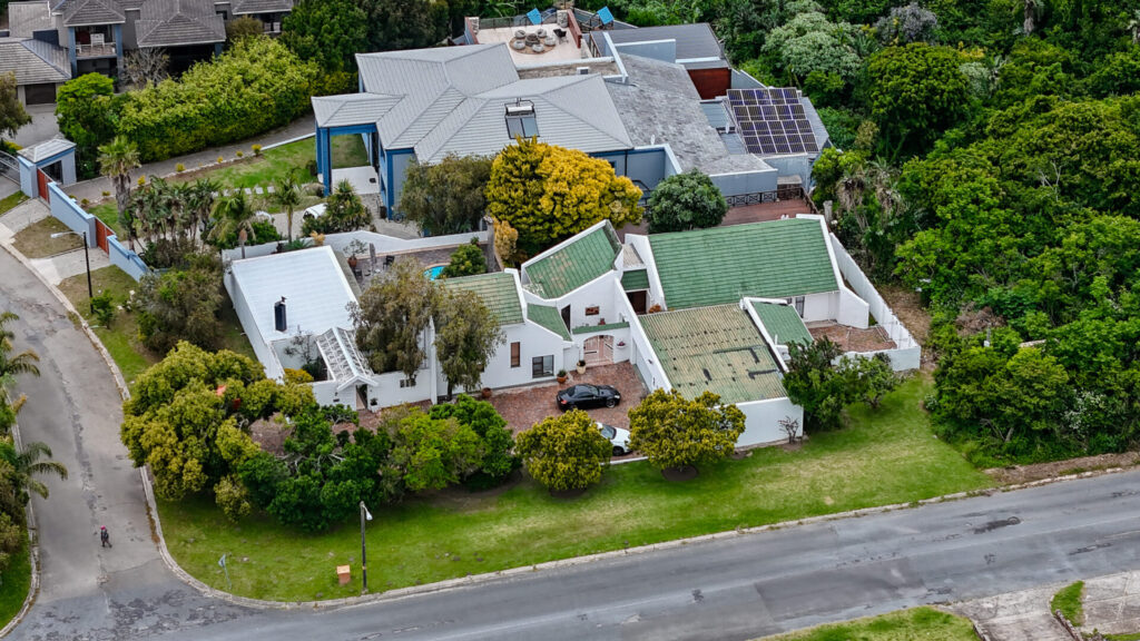 Aerial view of white homes and gardens beside a residential road