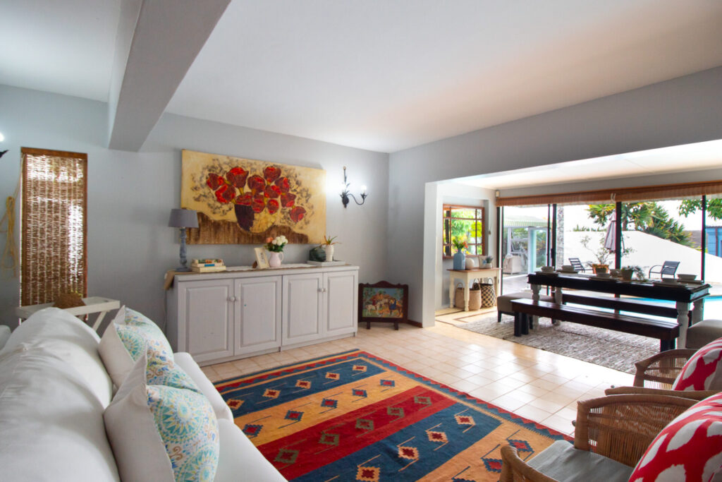 Living room with a colourful rug opening onto a pool-table area