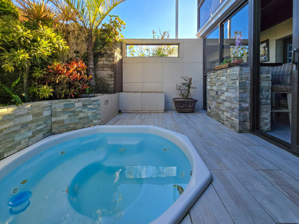 Small swimming pool beside a timber deck and stone-clad wall