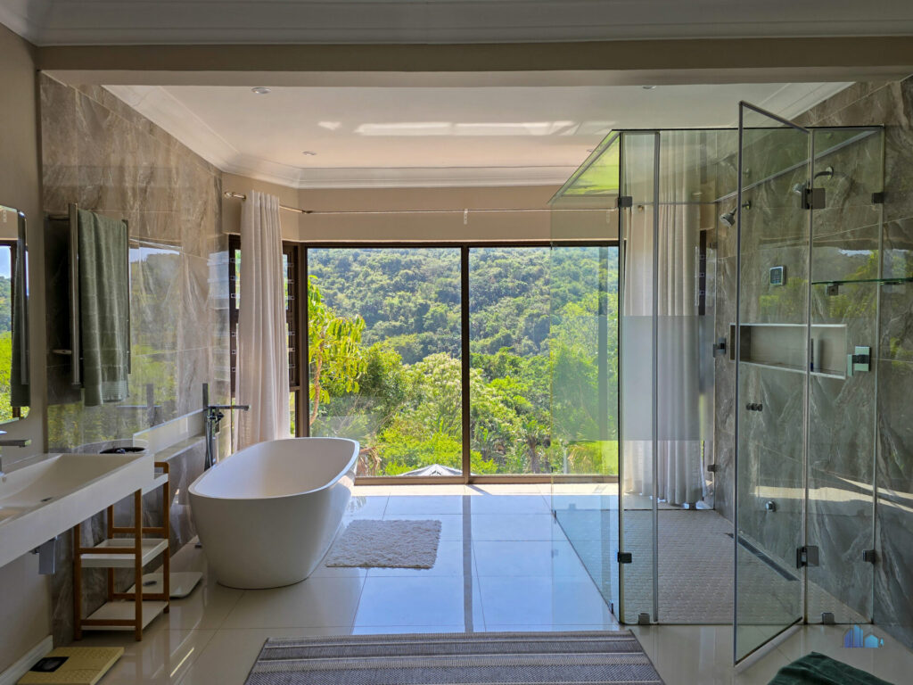 Bathroom with a freestanding bath, glass shower and large garden-facing window
