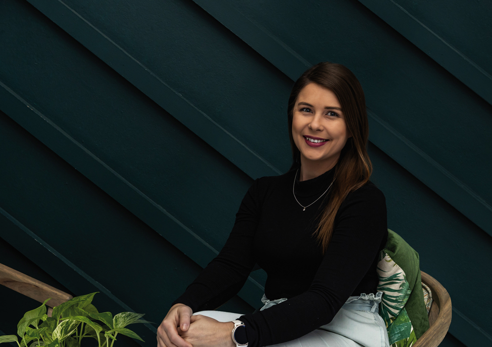 Portrait of a woman seated against a dark green feature wall