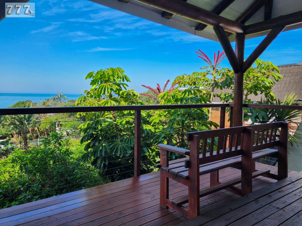 Covered timber balcony with a bench and leafy views