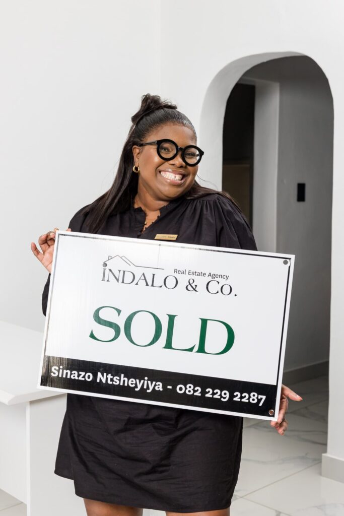 Woman holding an Indalo & Co. sold board inside a home