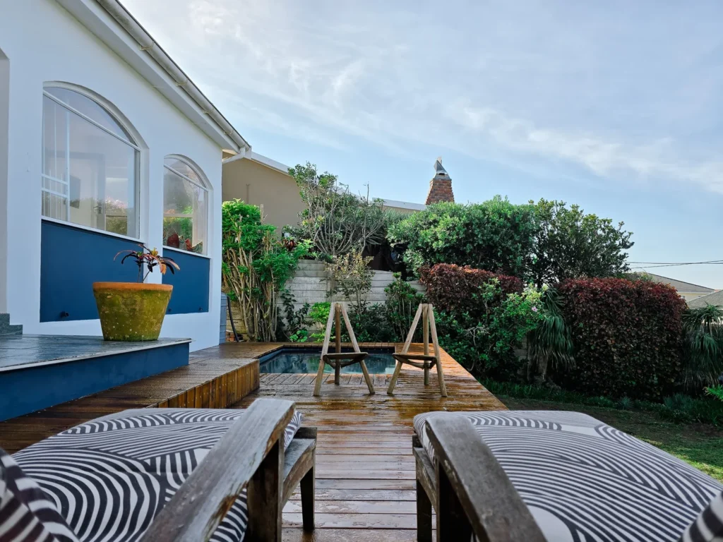 Outdoor pool deck with loungers beside a home